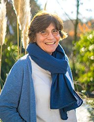 Christel Friedrich im Garten, mit blauem Schal, lächelnd